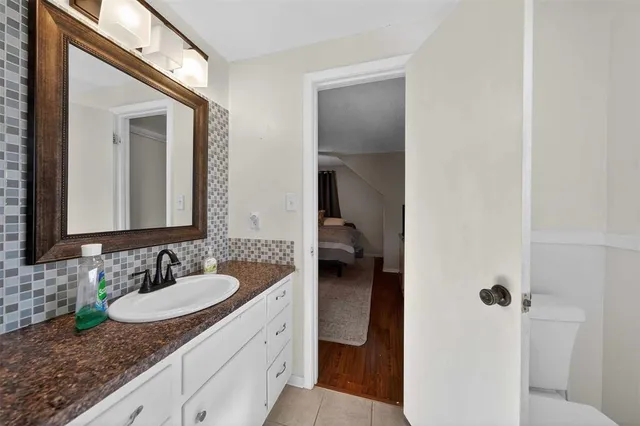 a en suite bathroom with a granite countertop sink and a mirror