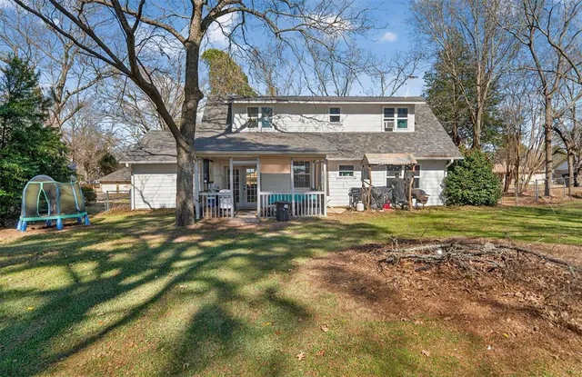 a view of a house with a big yard and large trees