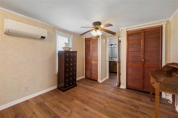 an empty room with wooden floor closet and windows