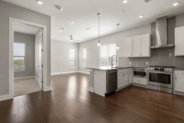 a large kitchen with stainless steel appliances granite countertop a stove a sink dishwasher and a refrigerator with wooden floor