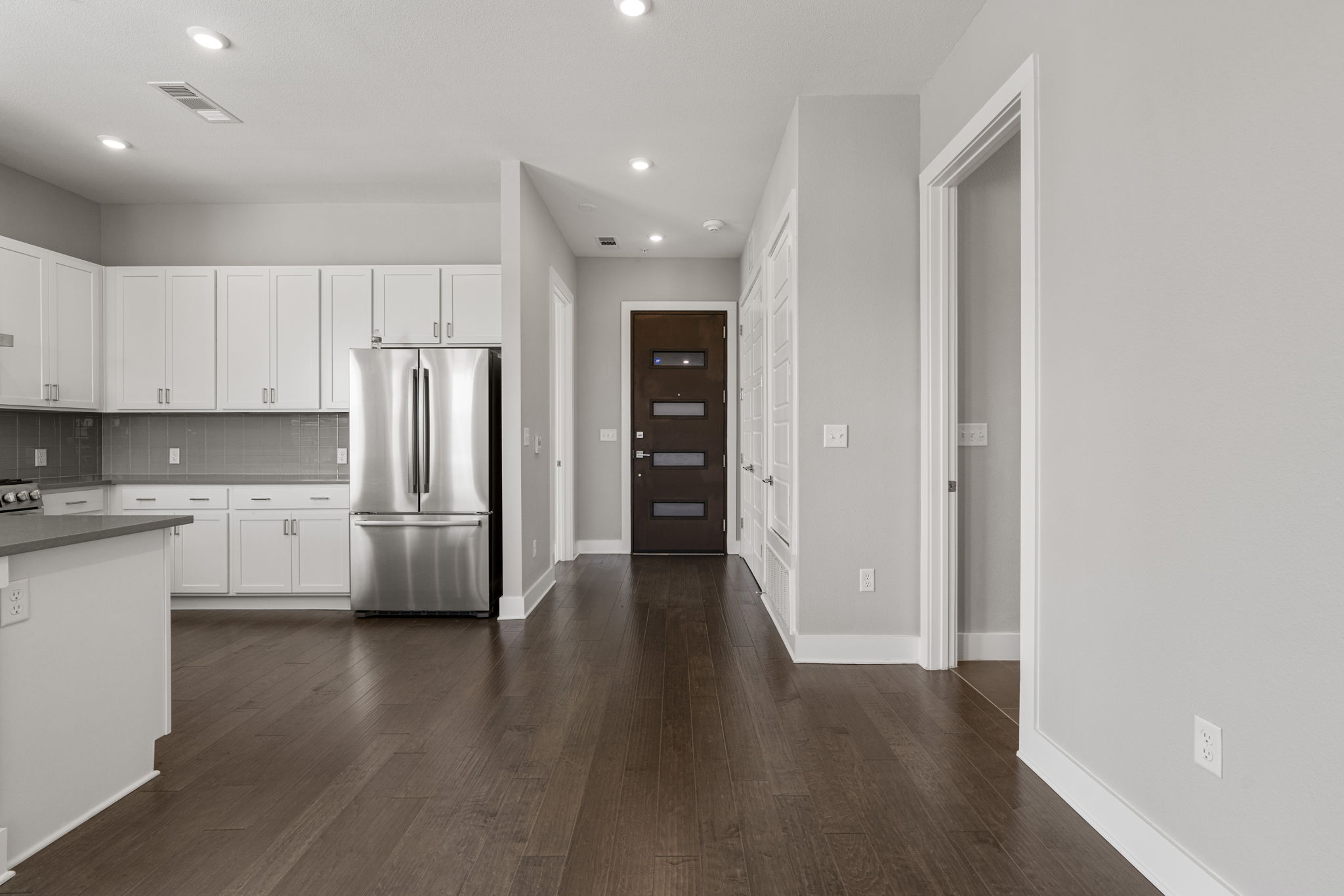 4501 Jackson Avenue, Unit 5205 Austin, TX 78731 - Photo 4 of 40 Kitchen with freestanding refrigerator, white cabinets, dark wood finished floors, decorative backsplash, and dark countertops