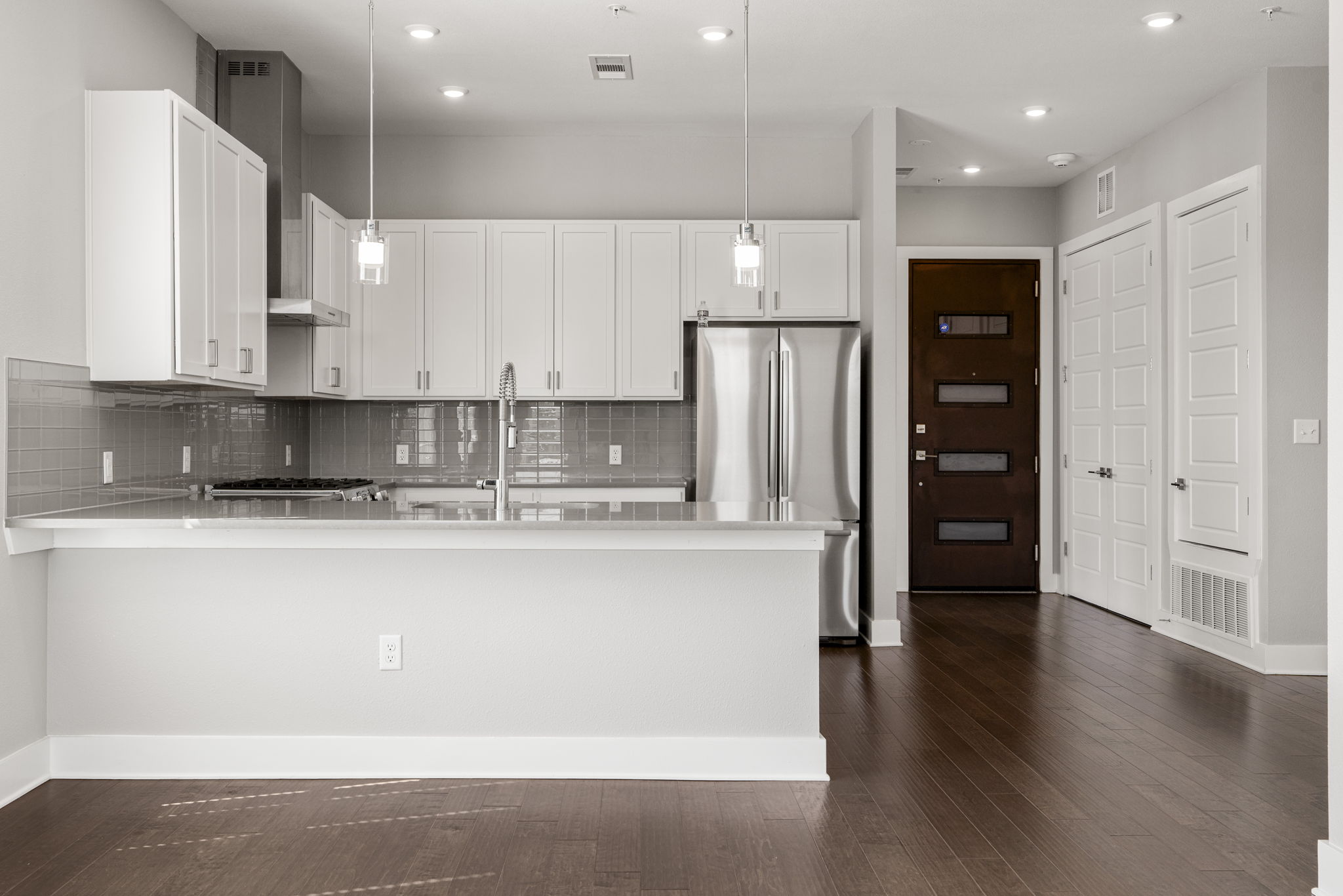 4501 Jackson Avenue, Unit 5205 Austin, TX 78731 - Photo 7 of 40 Kitchen with a peninsula, freestanding refrigerator, white cabinetry, tasteful backsplash, and dark wood-type flooring