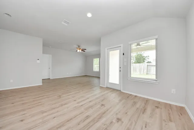 an empty room with wooden floor and windows