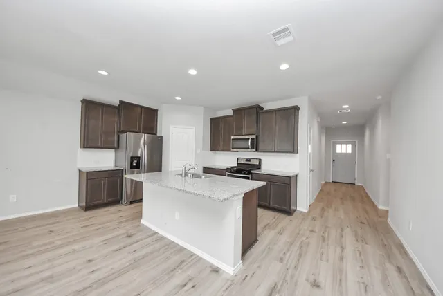 a large kitchen with a center island stainless steel appliances cabinets and wooden floor