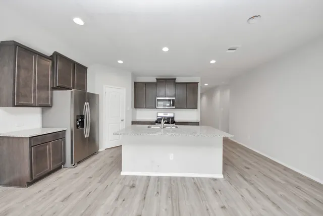 a large kitchen with stainless steel appliances granite countertop a large center island a sink a stove and a refrigerator