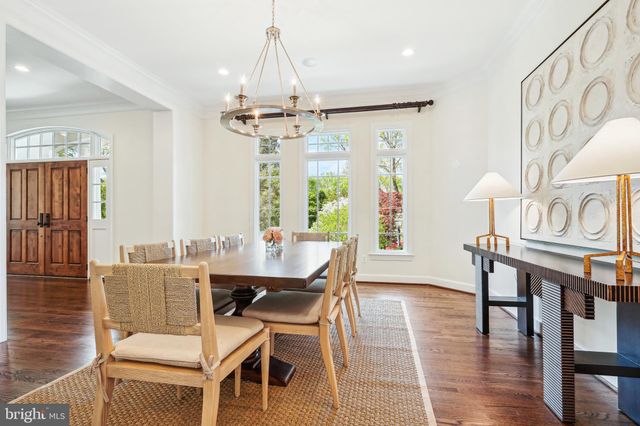 a dining room with wooden floor a chandelier a wooden table and chairs