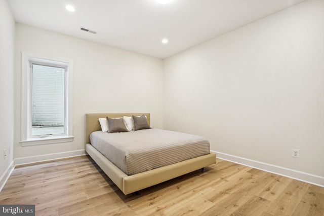 a view of an empty room with wooden floor fireplace and a window