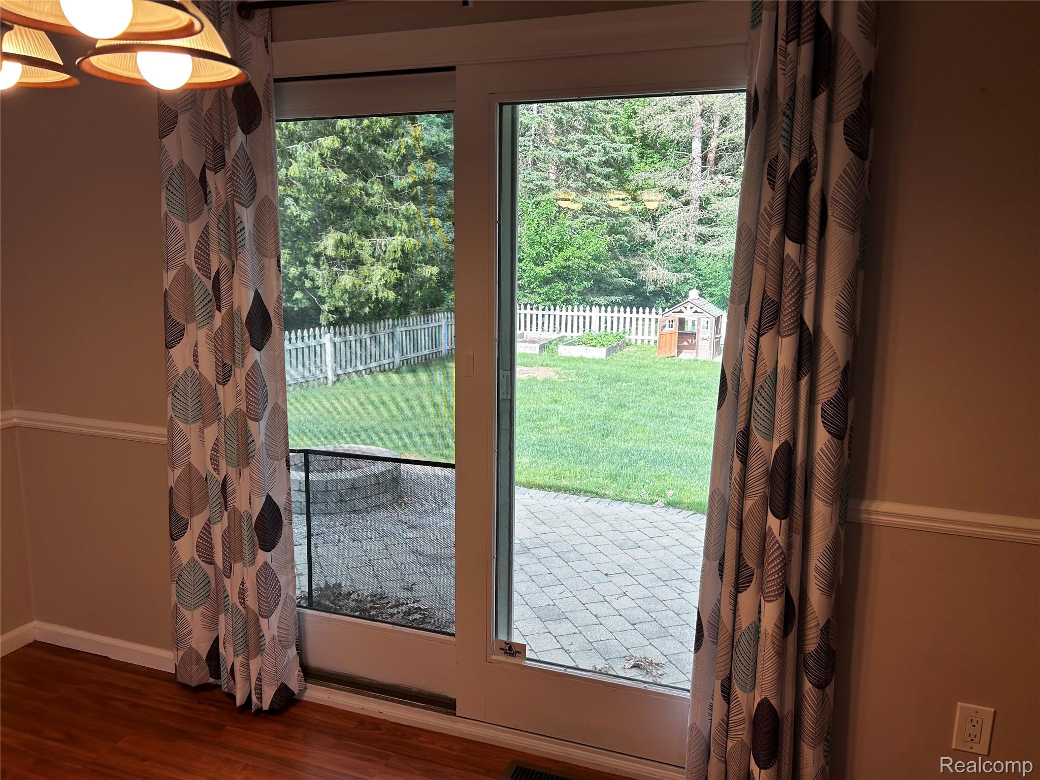 5440 Deland Road Flushing, MI 48433 - Photo 8 of 25 Sliding glass patio doors opening to an exterior paver patio with a built-in stone fire pit.