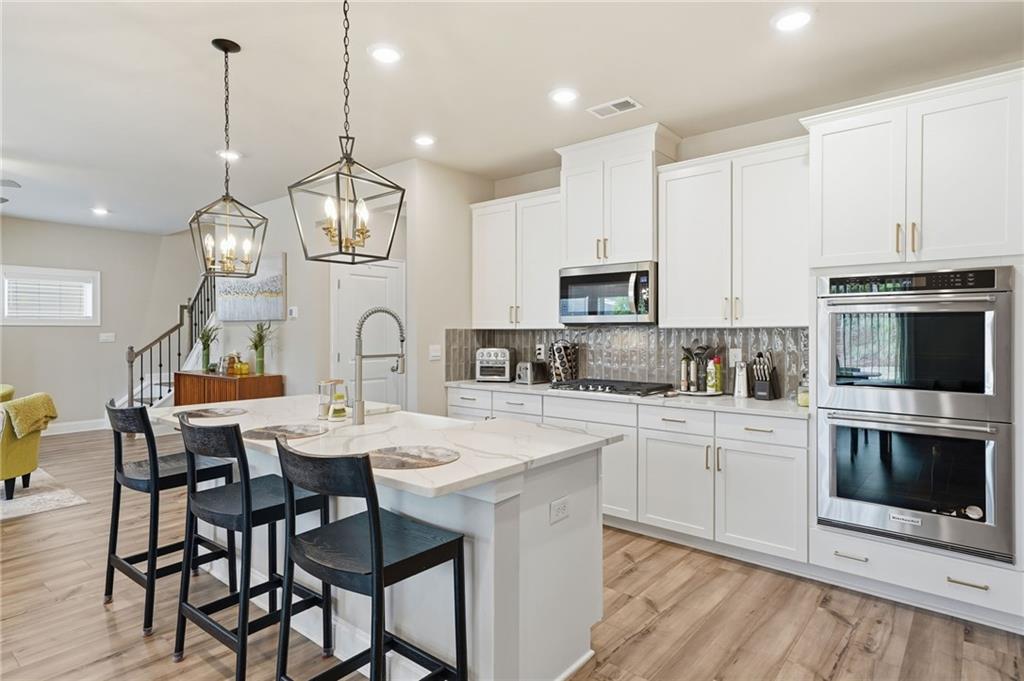 515 Cobblestone Circle Canton, GA 30115 - Photo 8 of 45 a kitchen with cabinets a sink stainless steel appliances and dining table with wooden floor