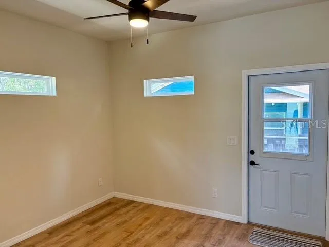 an empty room with a window and ceiling fan