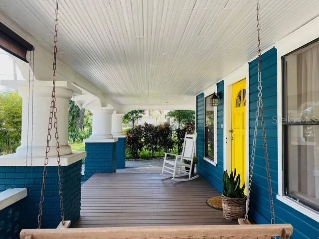 a living room with furniture potted plant floor to ceiling window and a flat screen tv