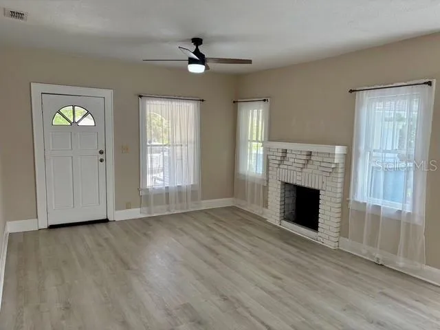 a view of empty room with wooden floor and fireplace