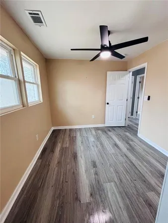 a view of empty room with wooden floor and fan