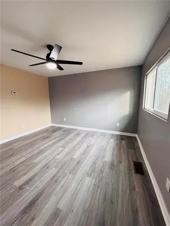 a view of empty room with wooden floor and fan