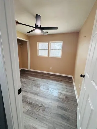 an empty room with wooden floor fan and windows