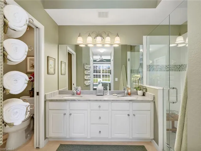 a bathroom with a granite countertop double vanity sink a mirror and a shower