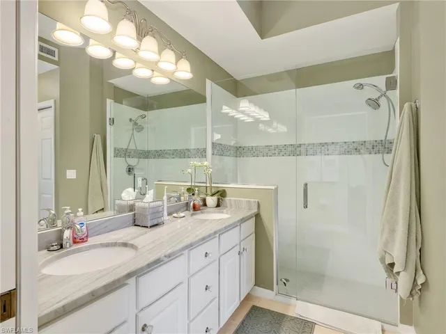 a bathroom with a double vanity sink mirror and shower