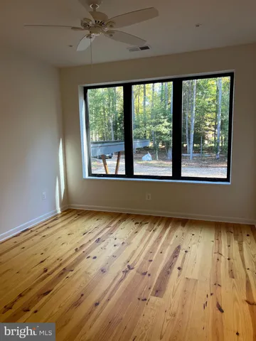 a view of an empty room with a window and wooden floor