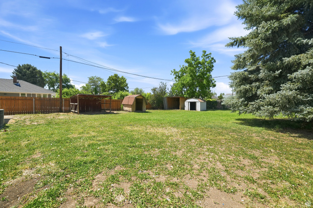 546 West 200 South Payson, UT 84651 - Photo 29 of 45 Spacious backyard with a grass area, two storage sheds, a covered outdoor structure, and a mature evergreen tree