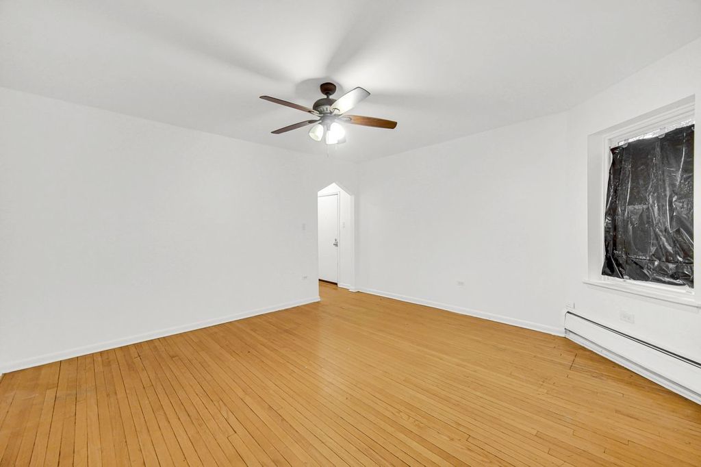 7017 South Merrill Avenue, Unit 305 Chicago, IL 60649 - Photo 11 of 20 a view of a big room with wooden floor a ceiling fan and window