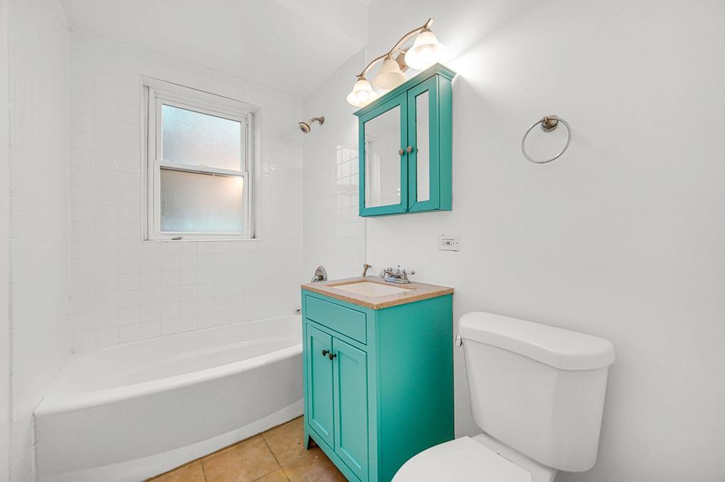 7017 South Merrill Avenue, Unit 305 Chicago, IL 60649 - Photo 7 of 20 a bathroom with a toilet sink vanity tub and mirror