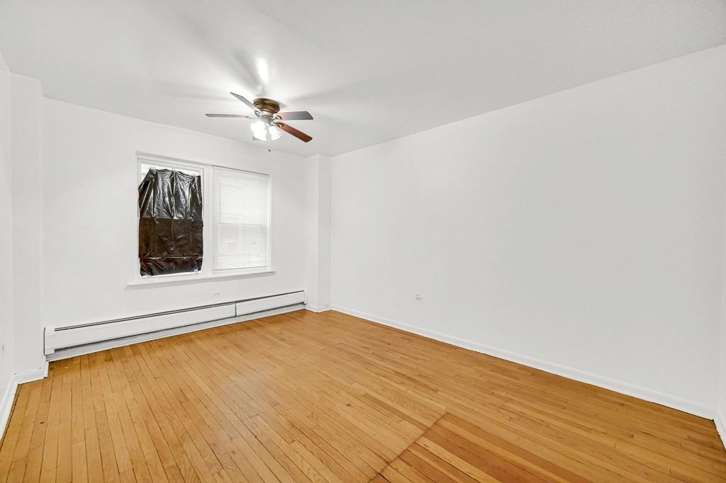 7017 South Merrill Avenue, Unit 305 Chicago, IL 60649 - Photo 10 of 20 an empty room with a window and ceiling fan