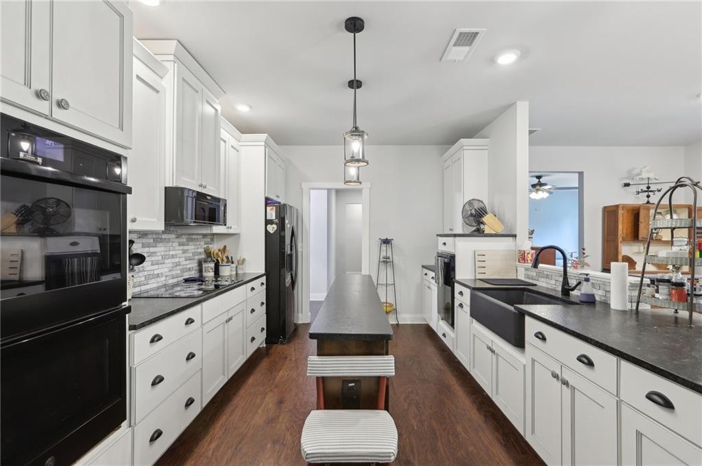 411 Johnson Road Locust Grove, GA 30248 - Photo 13 of 54 a kitchen with stainless steel appliances kitchen island granite countertop a stove a sink and a refrigerator