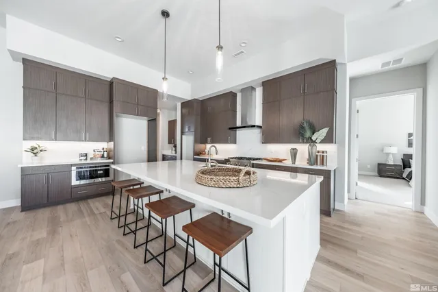 a kitchen with stainless steel appliances kitchen island granite countertop a stove a sink a refrigerator and white cabinets with wooden floor