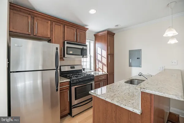 a kitchen with granite countertop a refrigerator stove and sink