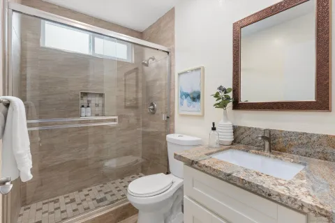 a bathroom with a granite countertop sink a toilet and shower