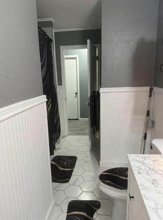 24133 Highway 157 Springhill, LA 71075 - Photo 16 of 19 Bathroom featuring hexagon tile flooring, white wainscoting, and a vanity with a marble-finish countertop