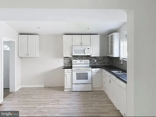 a kitchen with granite countertop white cabinets and white appliances