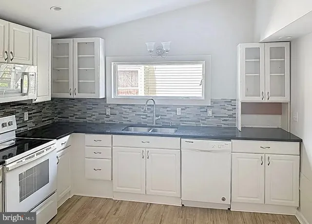 a kitchen with granite countertop white cabinets and white appliances