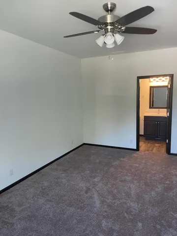 an empty room with a chandelier fan and windows