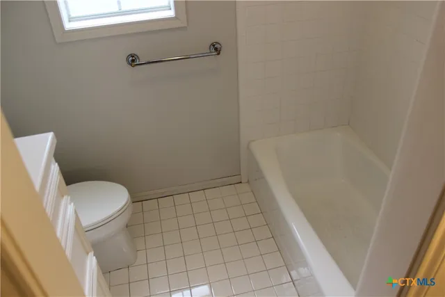 a bathroom with a granite countertop toilet and a bathtub