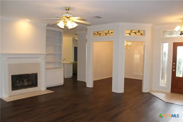 a view of an empty room with wooden floor and a fireplace