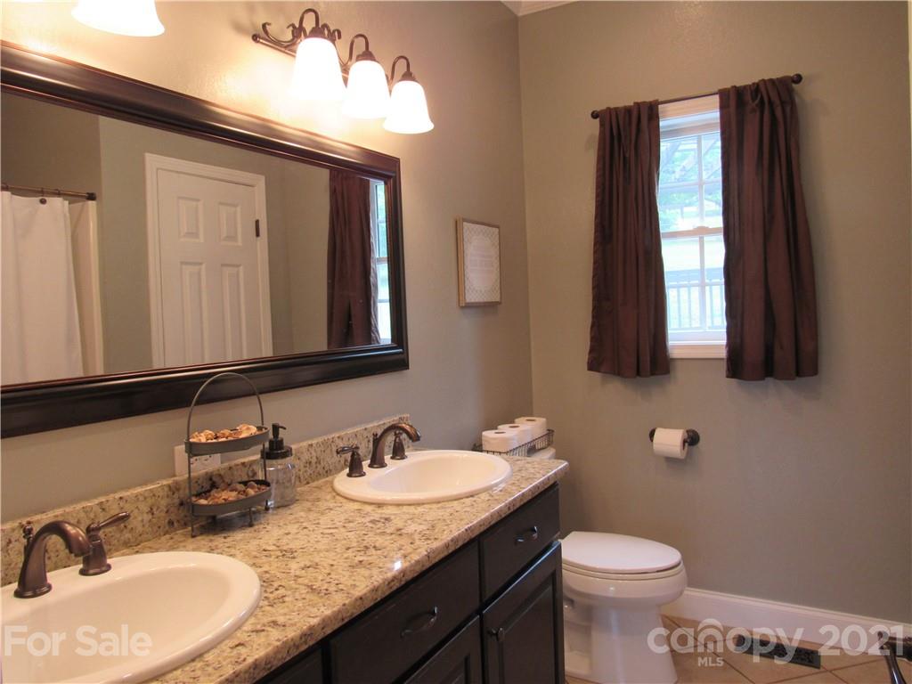 66 High Acres Road Waynesville, NC 28786 - Photo 16 of 41 a bathroom with a granite countertop sink toilet and mirror