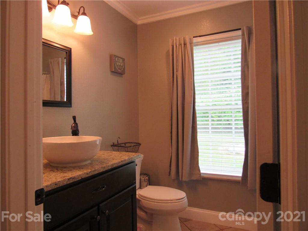 66 High Acres Road Waynesville, NC 28786 - Photo 24 of 41 a bathroom with a granite countertop sink toilet a mirror and a window