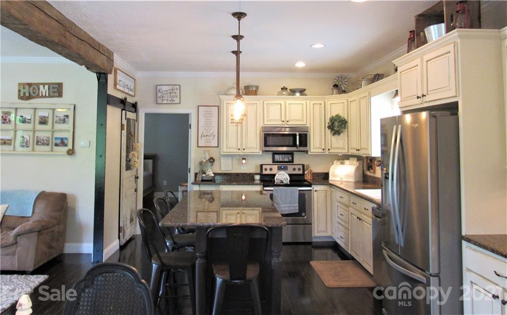 66 High Acres Road Waynesville, NC 28786 - Photo 9 of 41 a kitchen with stainless steel appliances granite countertop a refrigerator a stove a sink dishwasher a dining table and chairs with wooden floor