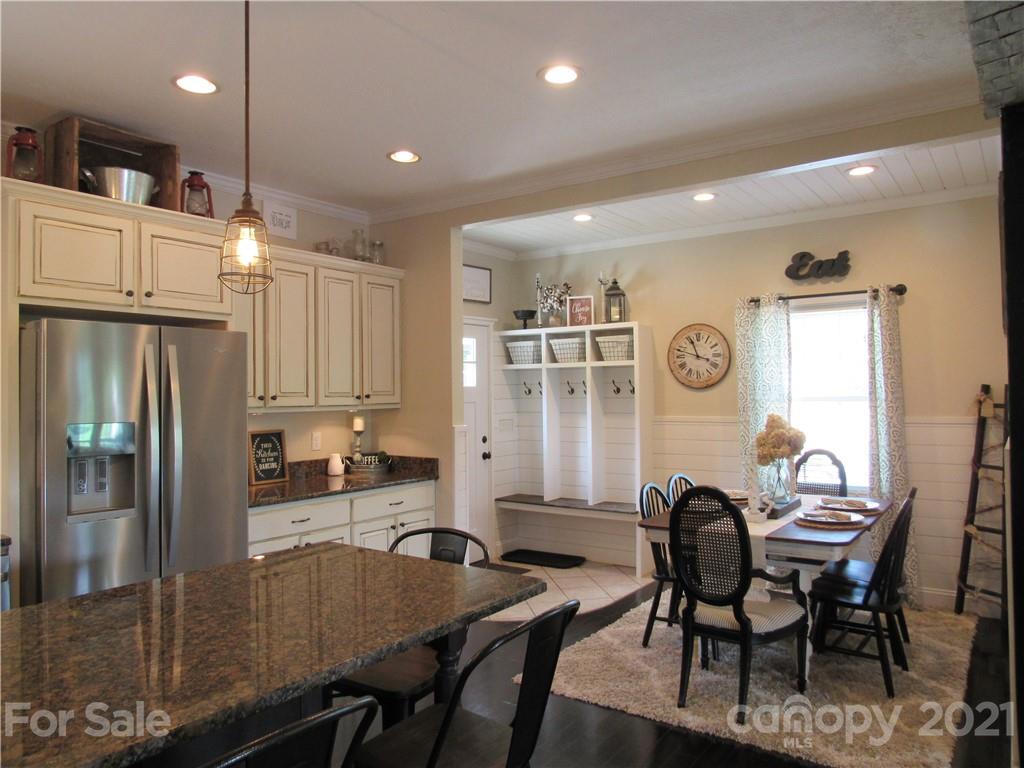 66 High Acres Road Waynesville, NC 28786 - Photo 10 of 41 a kitchen with granite countertop a refrigerator a stove a dining table and chairs with wooden floor