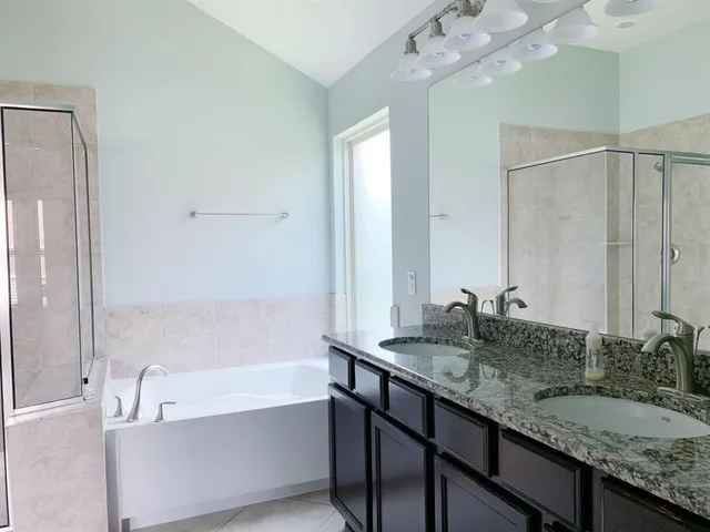 a bathroom with a granite countertop sink a large mirror and a bathtub