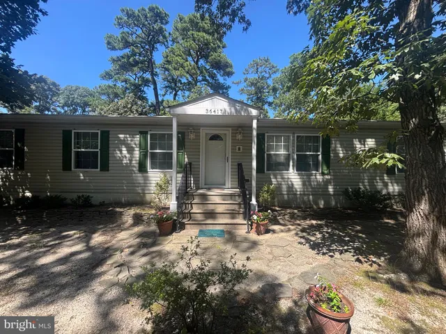 a front view of a house with a yard and potted plants