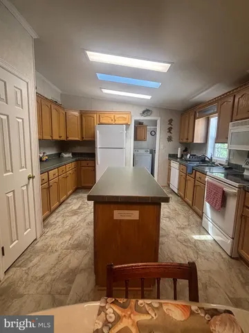 a kitchen with stainless steel appliances granite countertop a stove top oven a sink dishwasher a dining table and chairs with wooden floor