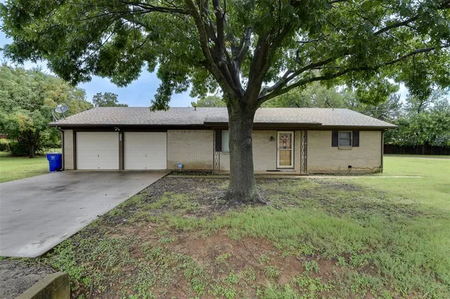 a view of a house with a yard and large tree