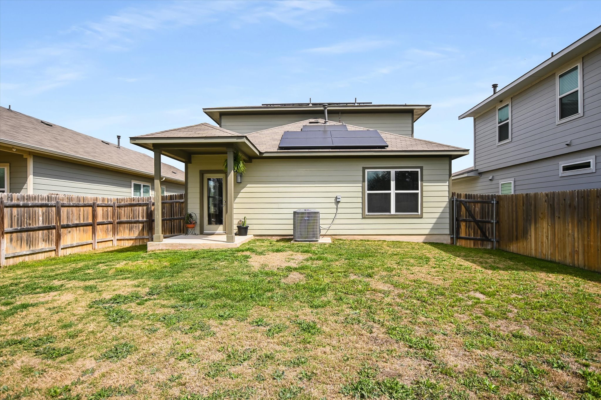 117 Deserti Road Leander, TX 78641 - Photo 19 of 21 Back of house featuring roof mounted solar panels, a patio area, a fenced backyard, and a gate