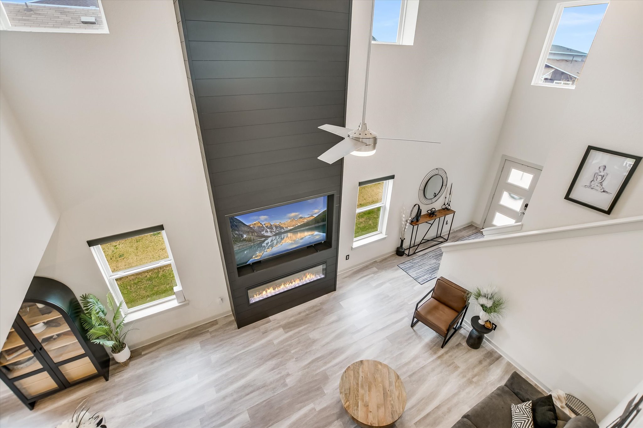 117 Deserti Road Leander, TX 78641 - Photo 6 of 21 Living room with a high ceiling, a glass covered fireplace, light wood-style floors, and a ceiling fan
