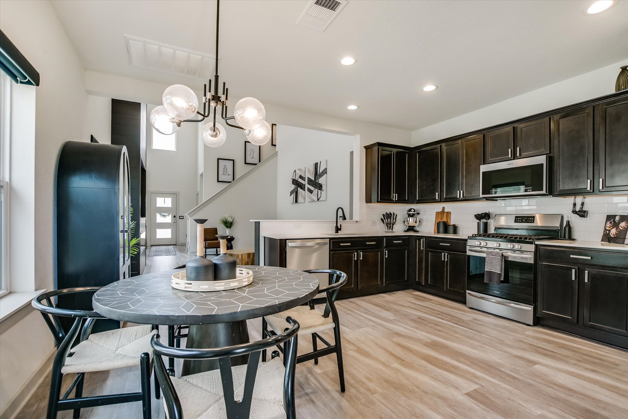 117 Deserti Road Leander, TX 78641 - Photo 7 of 21 Kitchen featuring stainless steel appliances, backsplash, light wood finished floors, a peninsula, and suspended lighting