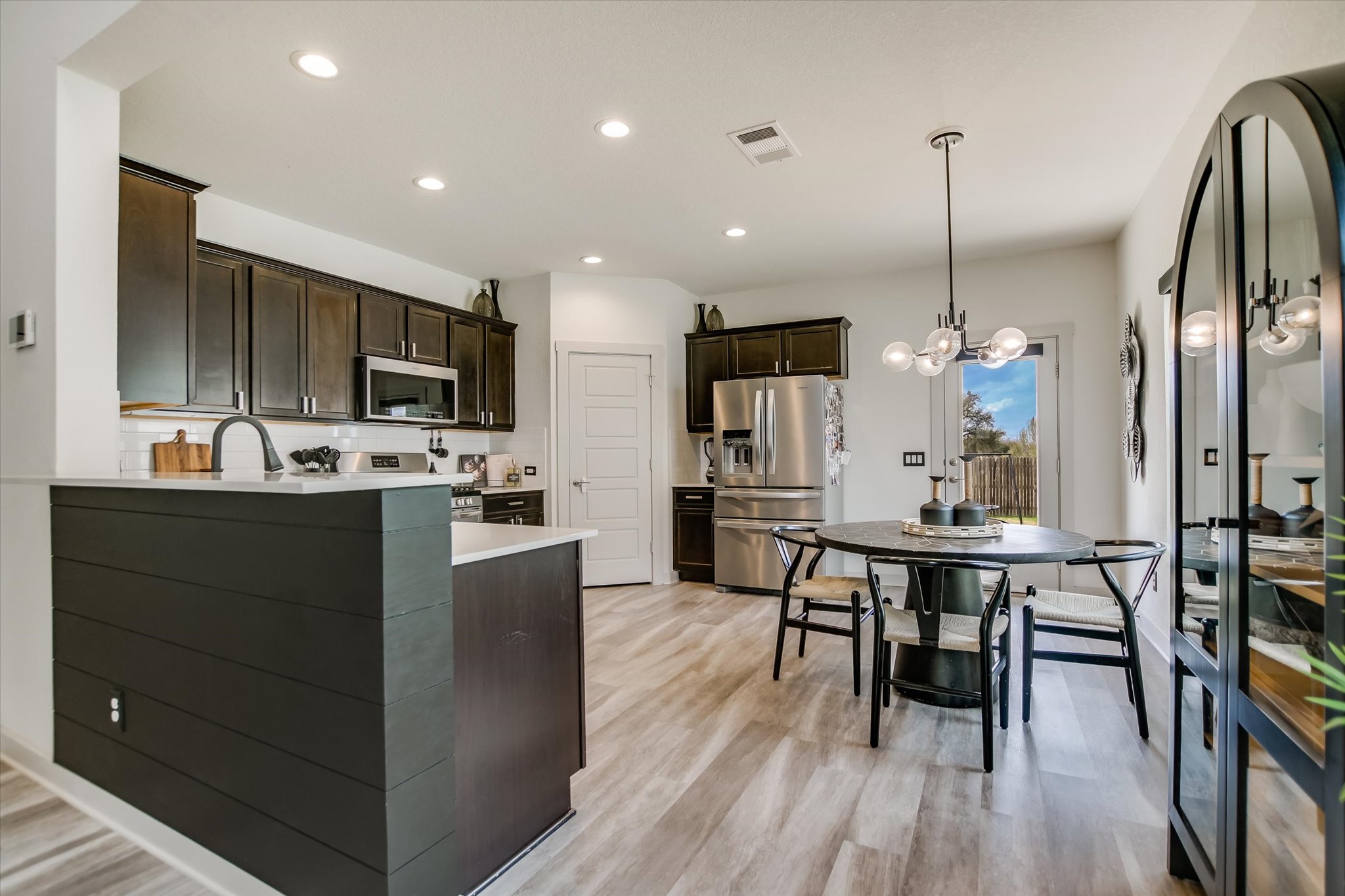 117 Deserti Road Leander, TX 78641 - Photo 8 of 21 Kitchen with dark wood finish cabinetry, stainless steel appliances, a peninsula, and light wood finished floors
