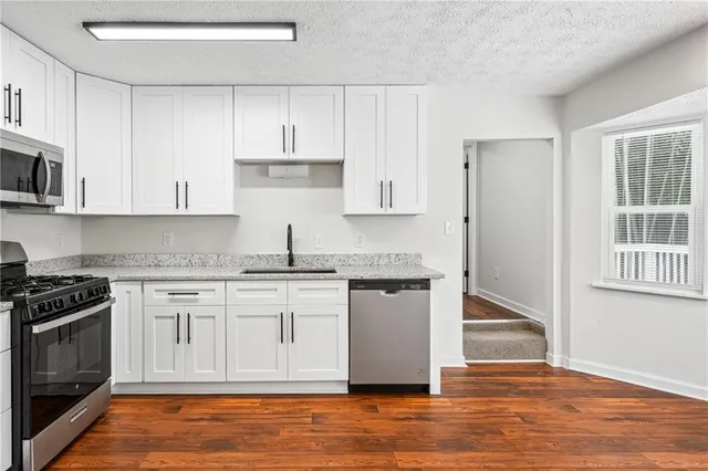 a kitchen with granite countertop wooden cabinets stainless steel appliances and a window