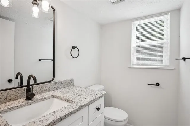a bathroom with a granite countertop sink a toilet and a mirror